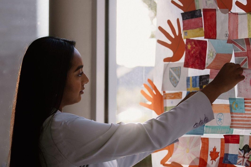 A woman adding sticky notes to a wall covered in coloured paper hands